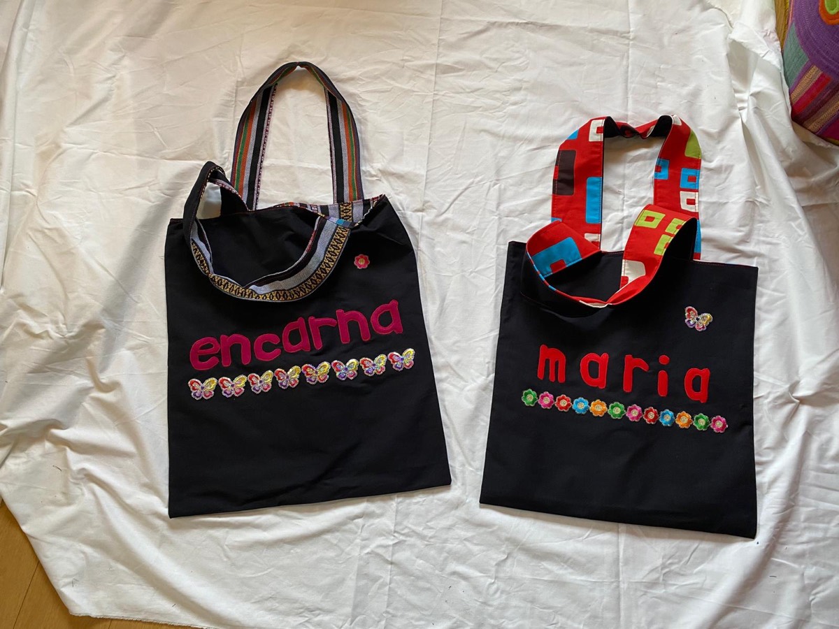 Dos bolsos negros, uno con encarna en rosa y otro con maria en rojo