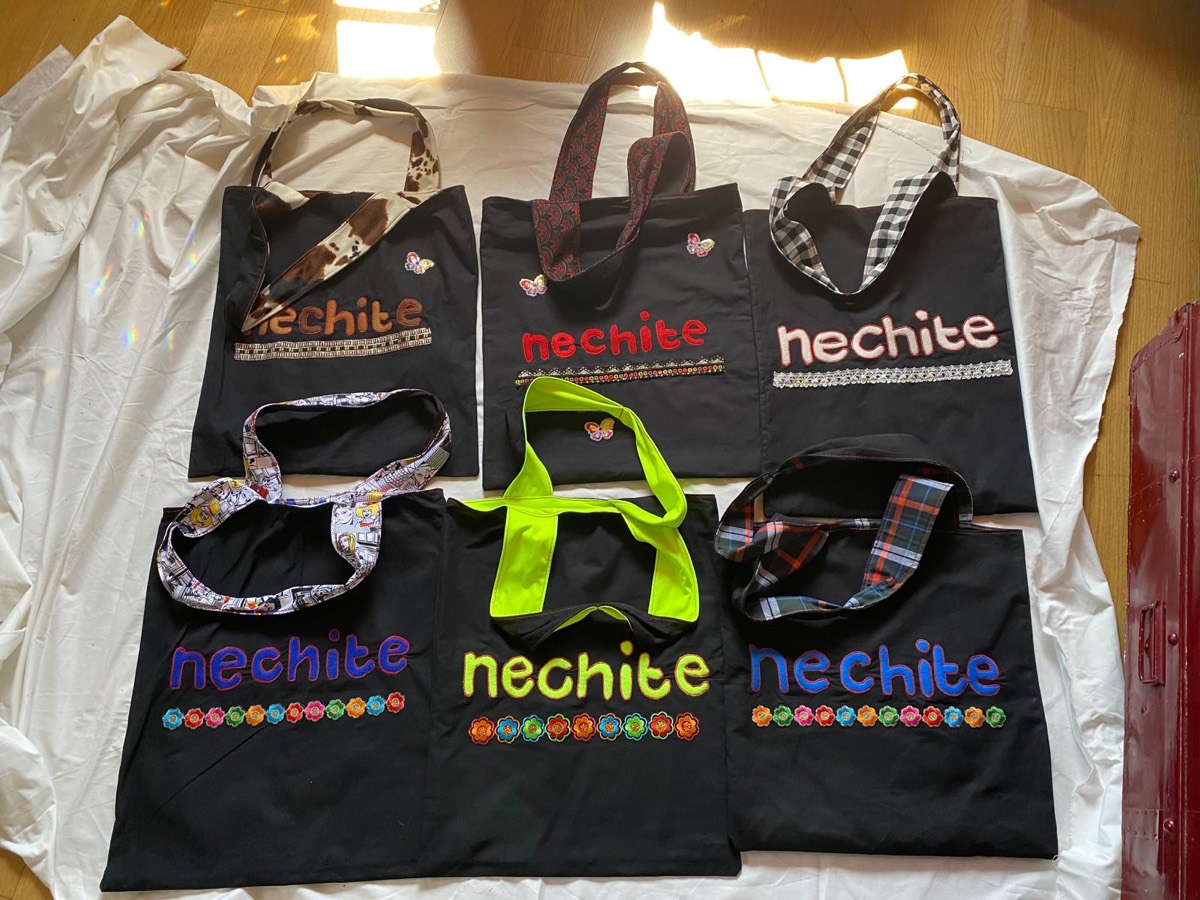 Seis bolsos negros con el nombre nechite en distintos colores y con asas de telas diferentes